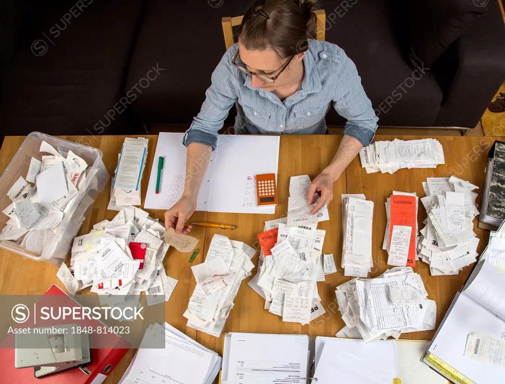Woman sorting documents, records, invoices and receipts on a desk, for the tax return