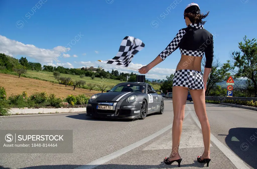 Grid girl holding a chequered flag, Porsche 911, Mille Miglia vintage car race, Assisi, Umbria, Italy