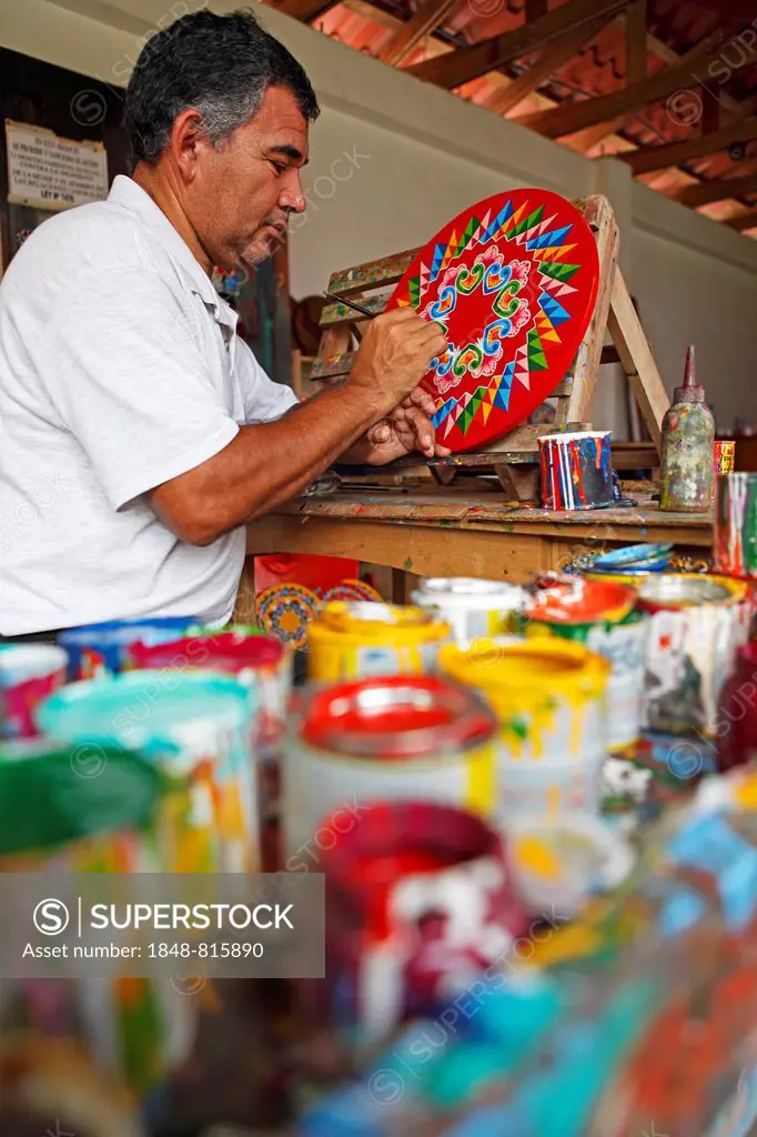 Man painting the hub of a traditional oxcart or Carreta, Sarchi, Alajuela province, Costa Rica