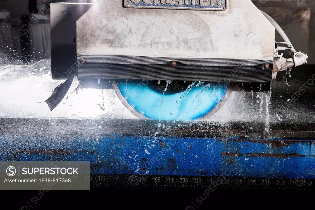 A wet-cutting machine cutting a stone slab