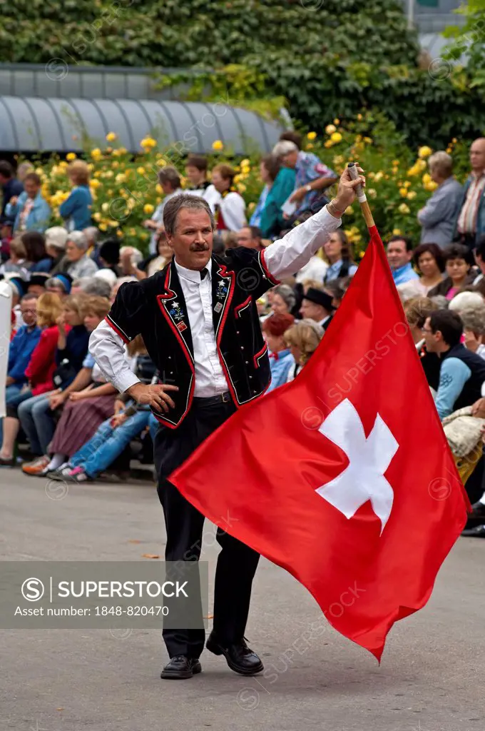 Flag-waver with a Swiss flag at a costume parade, Interlaken, Canton of Bern, Switzerland