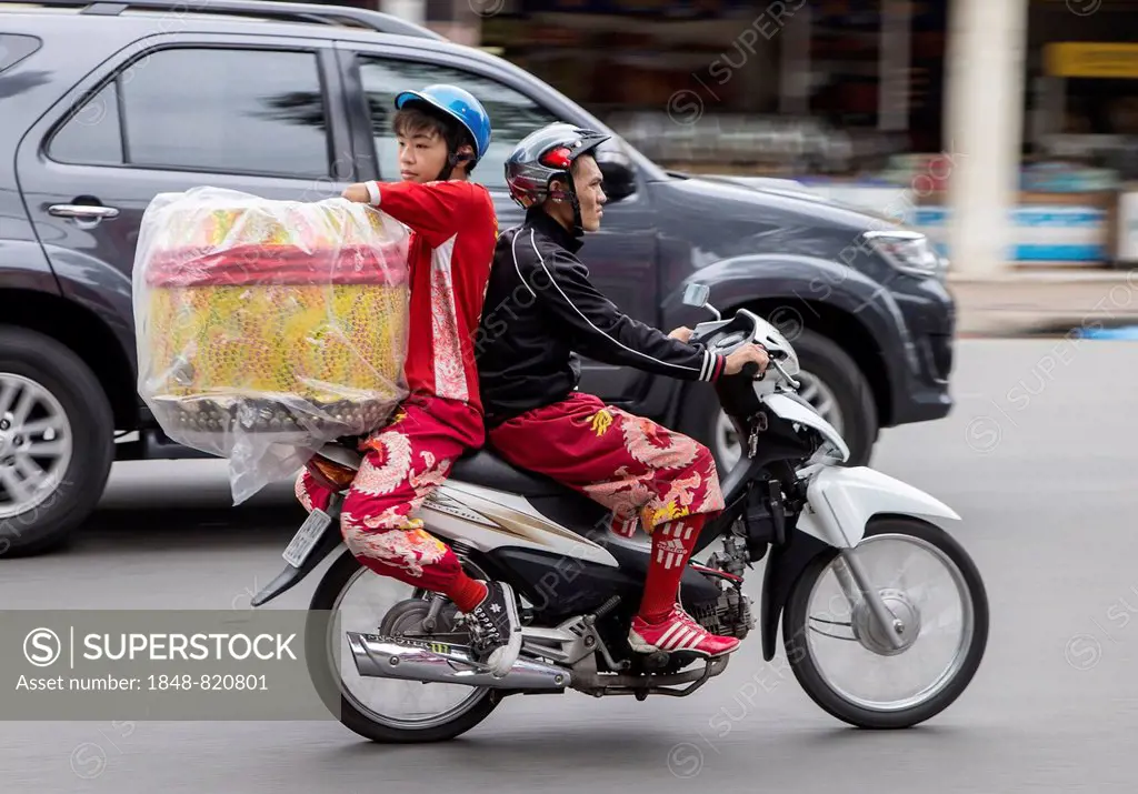 Boy and man transporting a large object on a motorcycle, Ho Chi Minh City, Vietnam