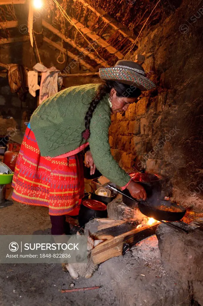 Young woman cooking on an open fire in her traditional kitchen, Union Potrero, Quispillacta, Ayacucho, Peru