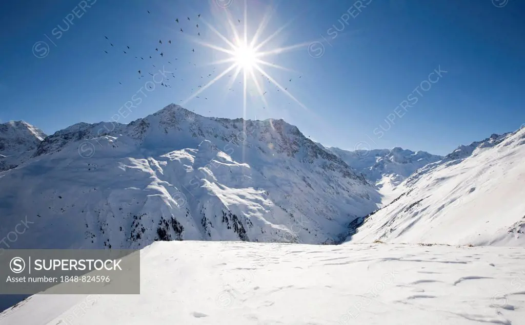 Birds circling the sun, winter landscape in the Pitztal, Taschachferner, North Tyrol, Austria