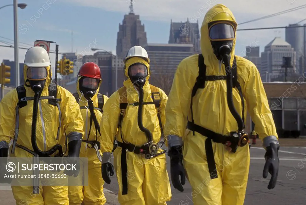 During a training session for workers dealing with toxic chemical spills, participants in protective suits walk down the street, Detroit, Michigan, US...