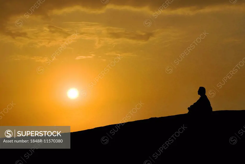 Buddhist meditating at sunset