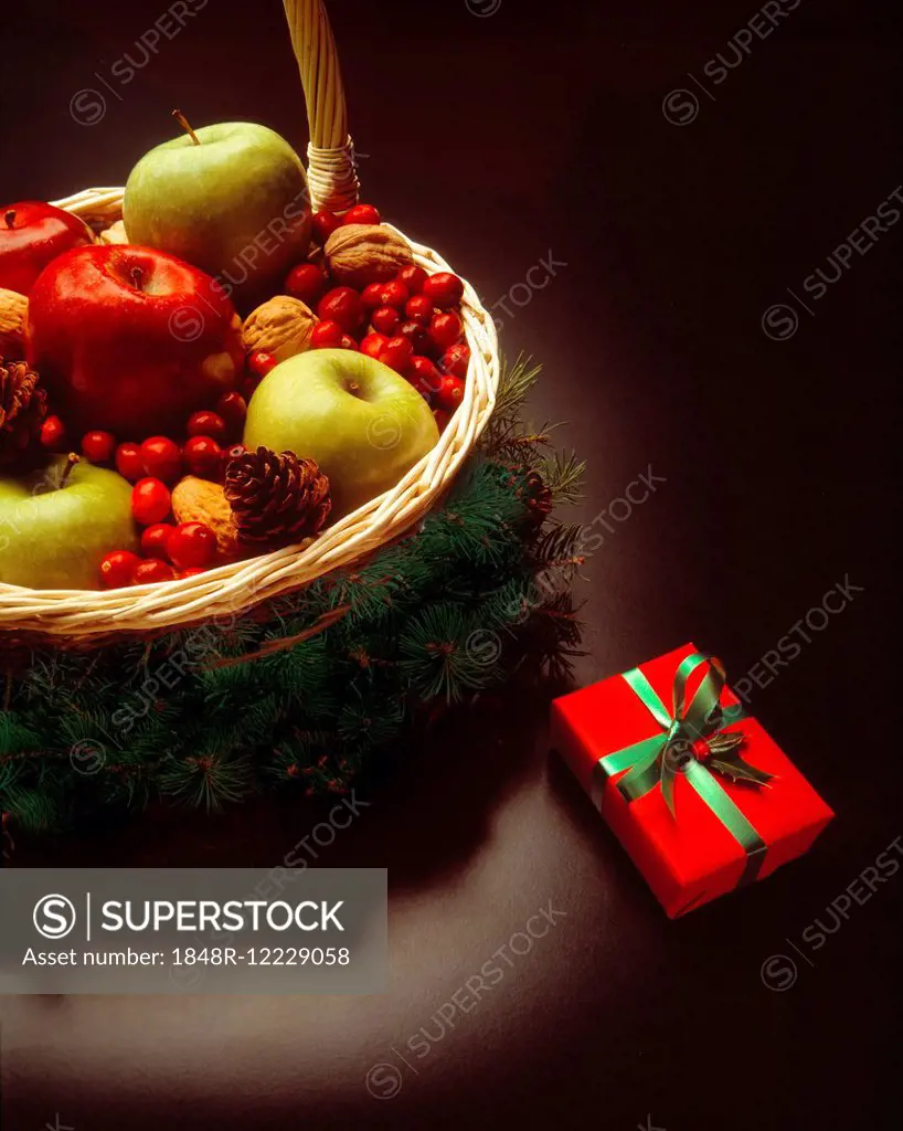 Christmas present beside festive basket filled with fruits and nuts