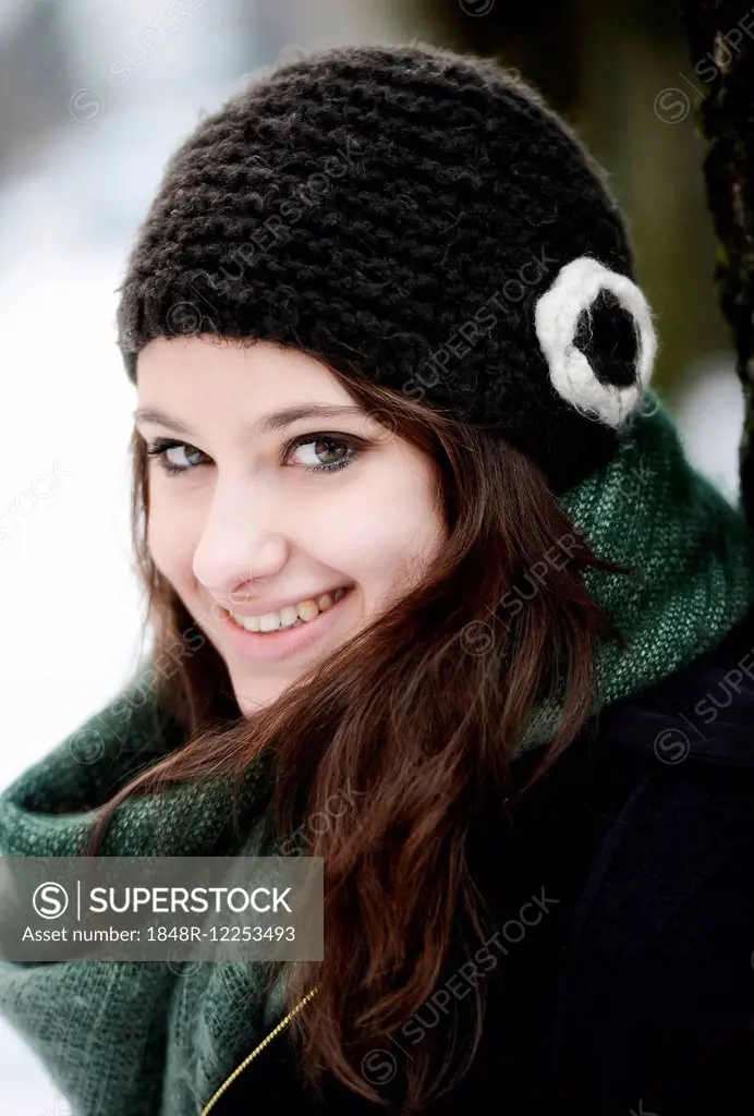 Smiling young woman wearing hat and scarf in winter, portrait