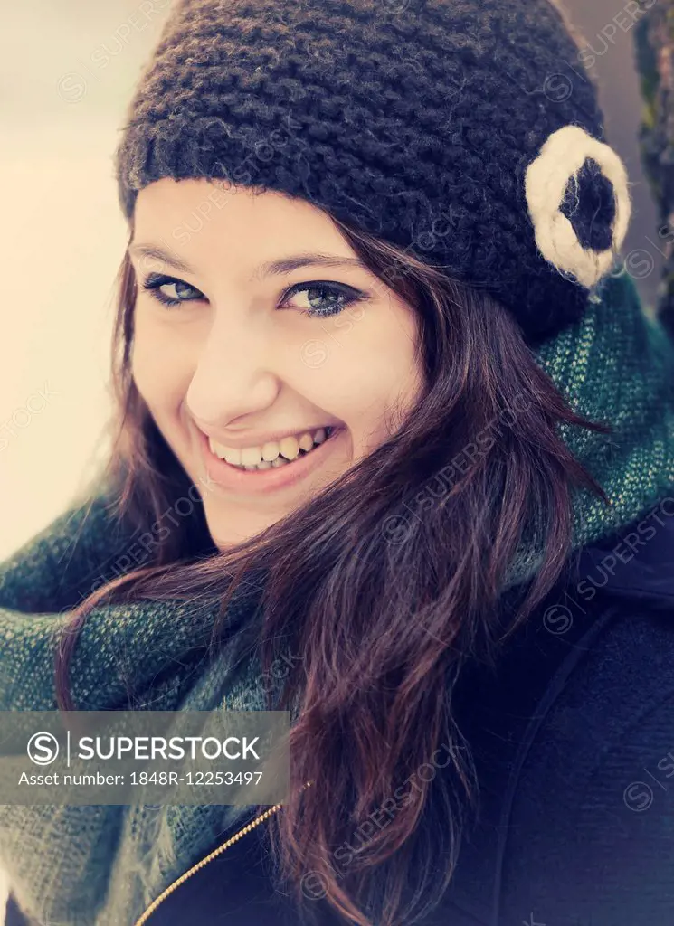 Smiling young woman wearing hat and scarf in winter, portrait