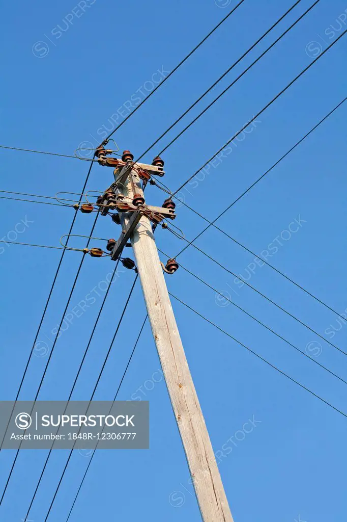 Electricity pylon with power lines and isolators against blue sky