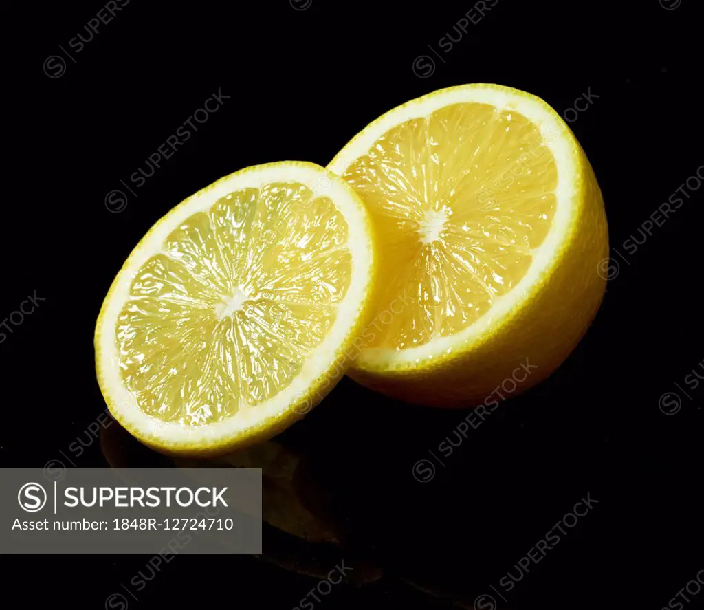 Lemon (Citrus limon), slice, sliced in half, against a black background