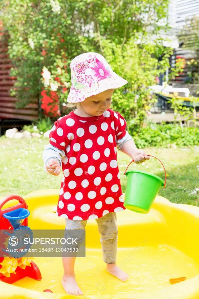 Toddler, little girl playing with water in a wading pool