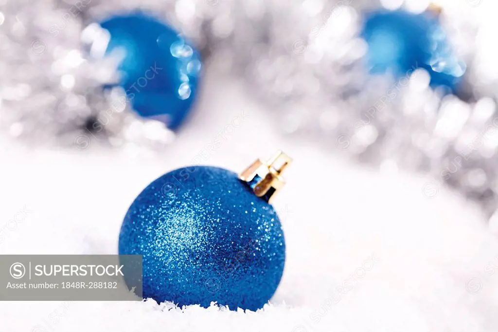 Blue glitter Christmas tree balls on snow with Christmas decorations