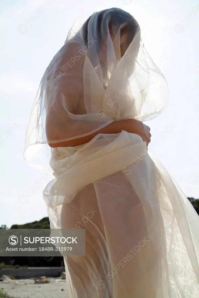 Naked young woman wrapped in transparent cloth on the beach in Mallorca, Spain, Europe