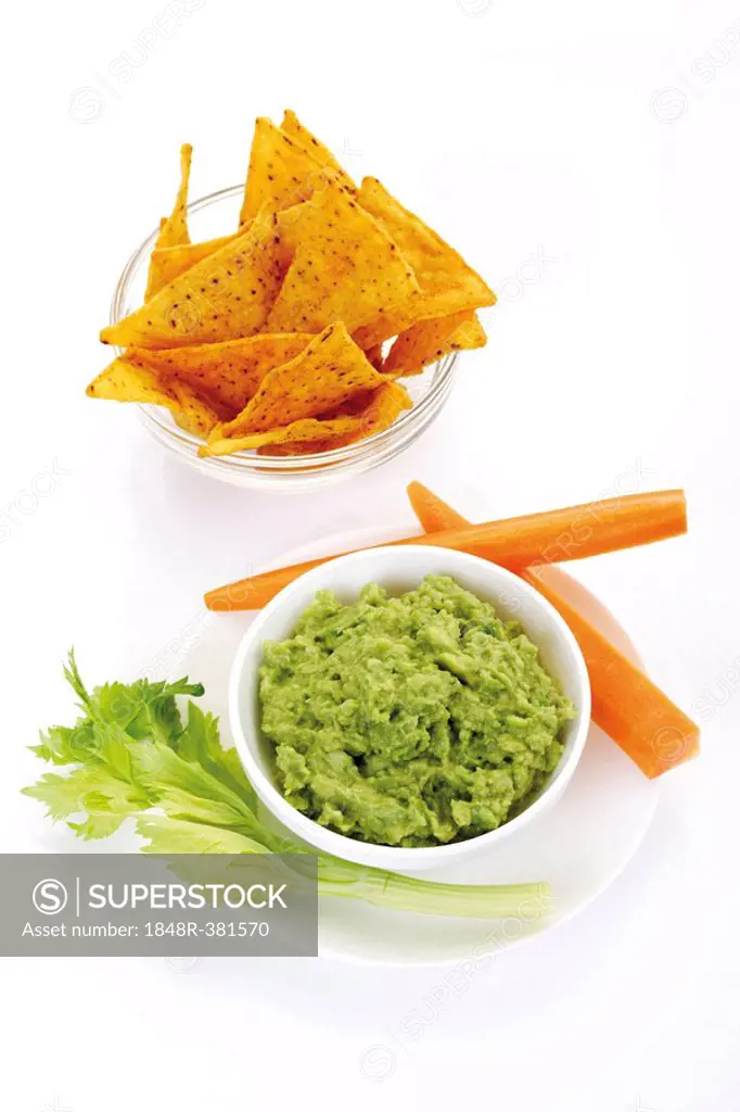 Nachos and avocado dip (guacamole) garnished with carrots and celery