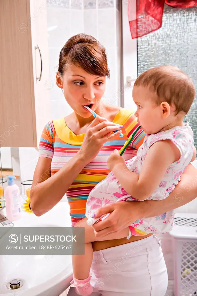 Mother and daughter brushing teeth together, bathroom