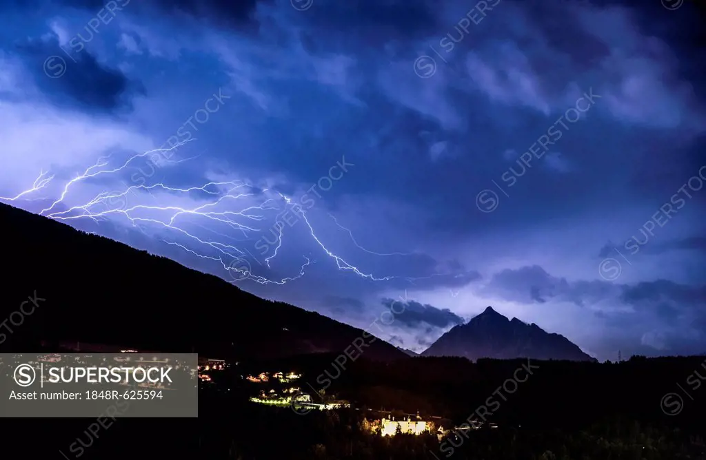 Ominous clouds and lightning bolts from thunderclouds over the Stubai Valley near Innsbruck, in the back Mt. Serles and Aldrans and Lans villages, nig...