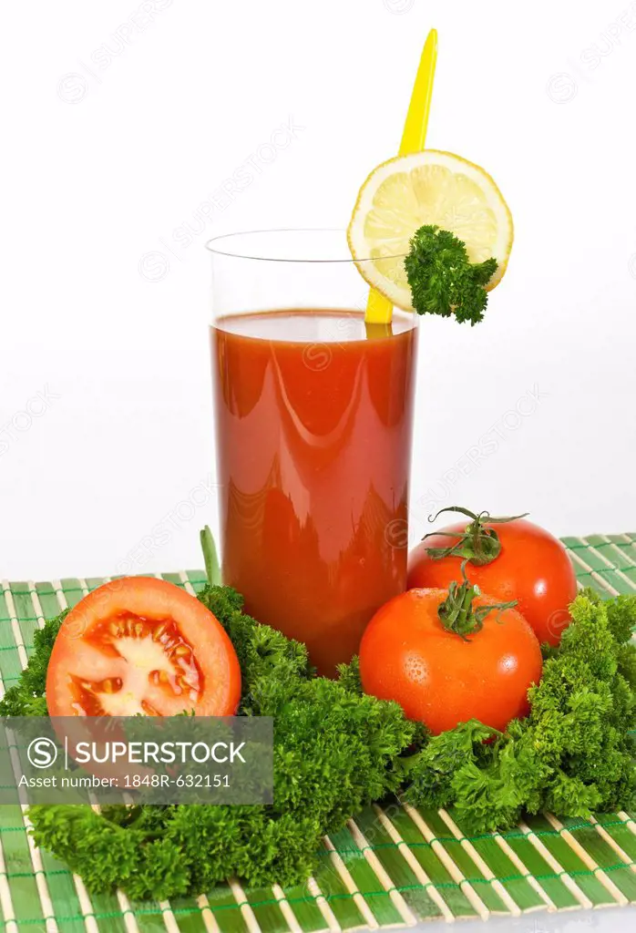 Tomato juice in a glass with tomatoes, lemon and parsley
