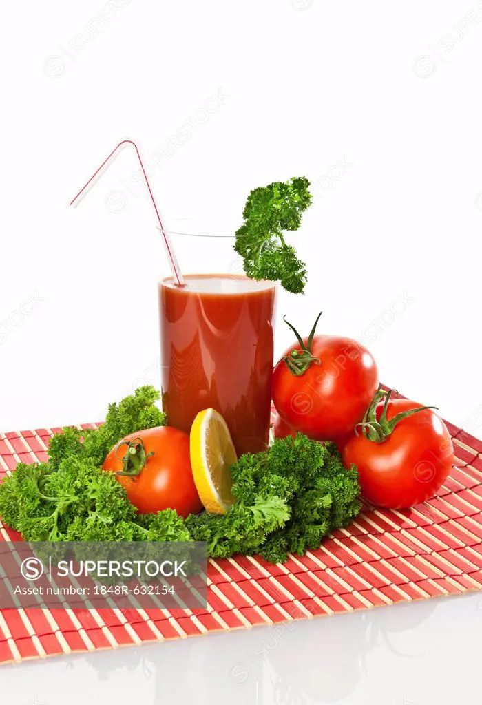 Tomato juice in a glass with tomatoes, lemon and parsley