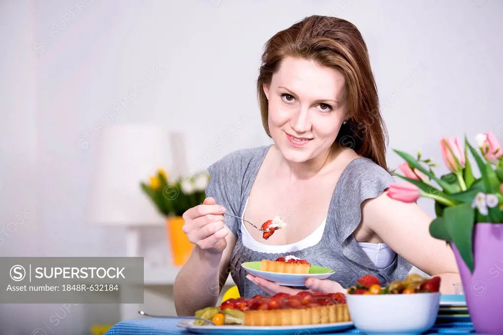 A young woman eating fresh strawberry cake