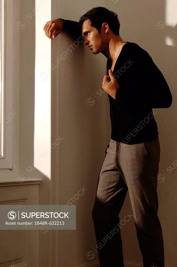 Young man leaning against apartment wall