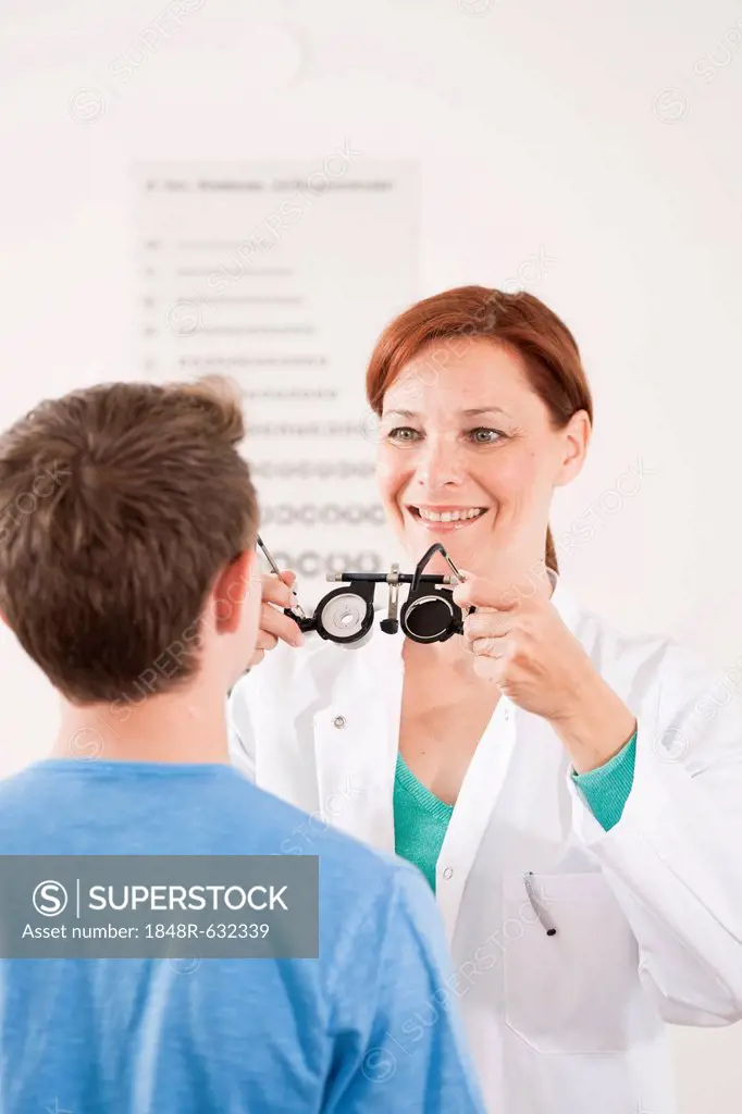 Ophthalmologist putting a pair of glasses for a vision test on a teenage boy