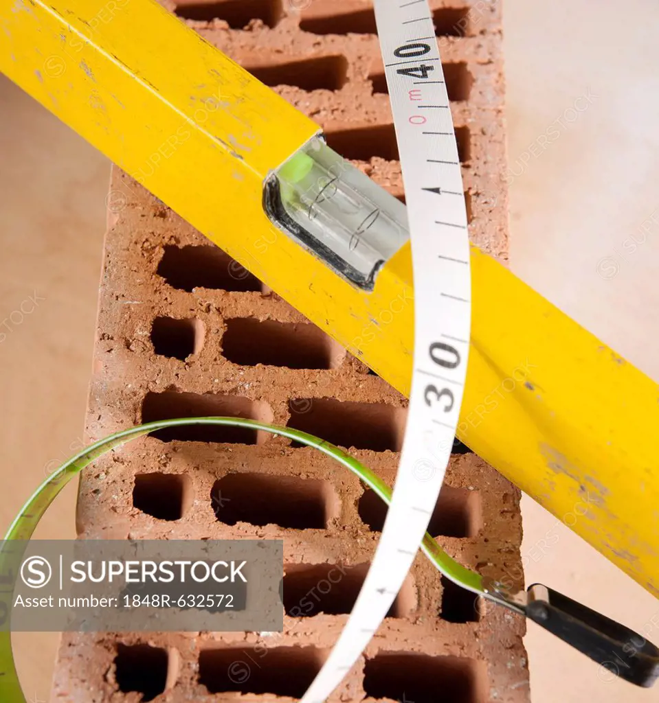 Spirit level and a measuring tape on a brick