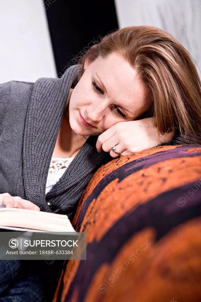 Young woman reading a book in the living room
