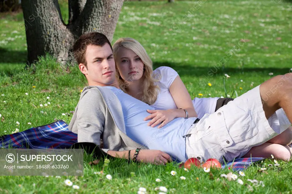 Young couple lying on a picnic blanket in a park, spring