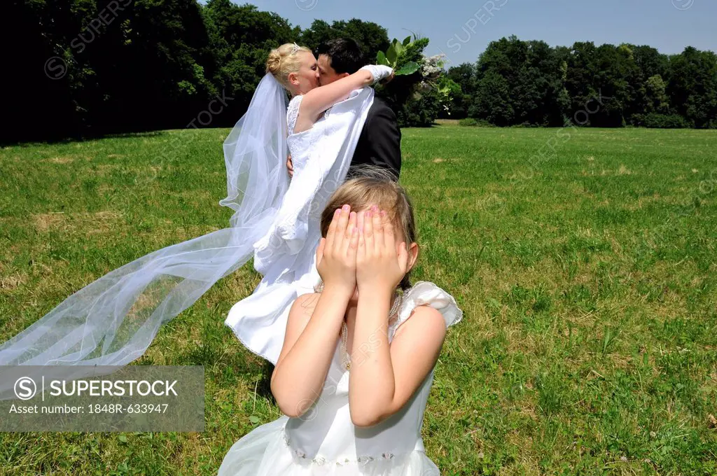 Wedding, young couple kissing, little coy girl covering her eyes