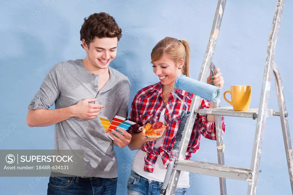 Young couple using colour cards to select a wall paint colour