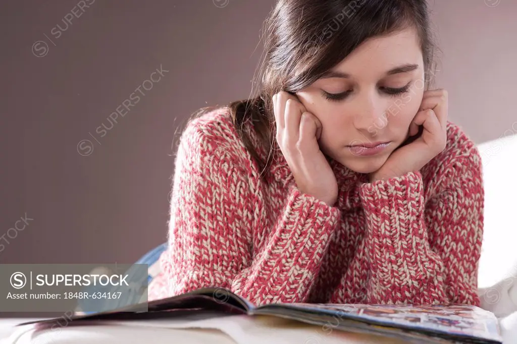 Girl lying on a couch and reading a magazine