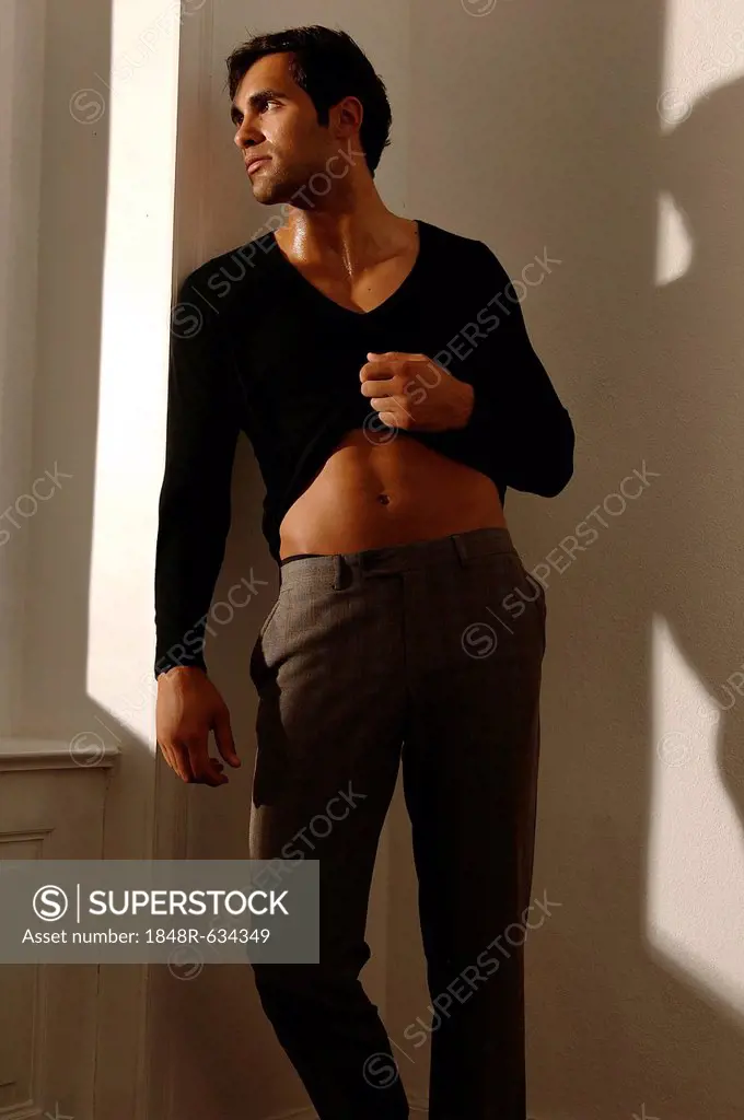 Young man leaning against apartment wall