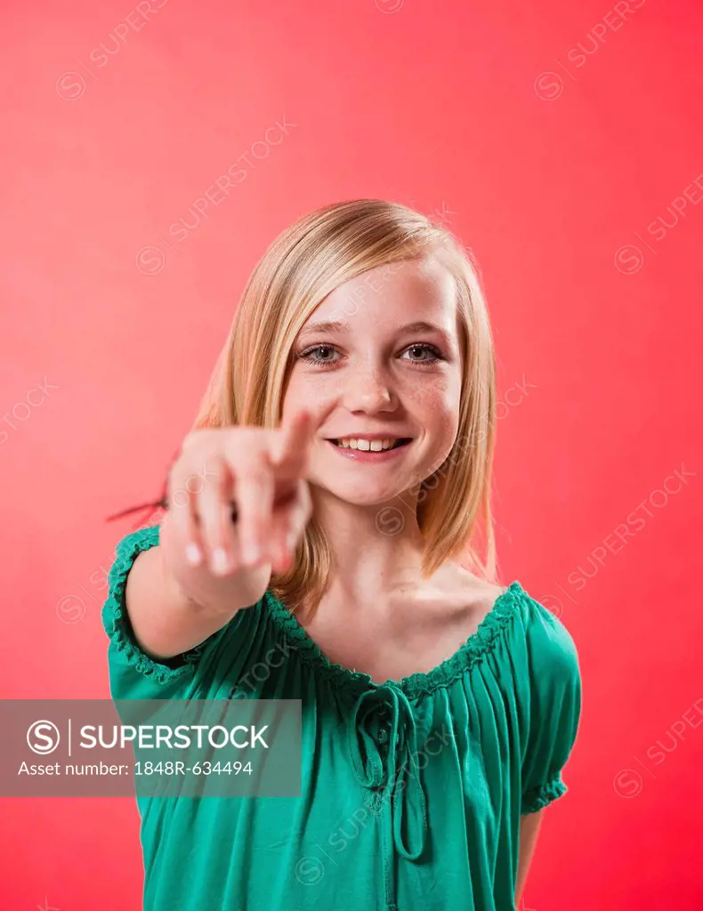 Smiling girl pointing her index finger towards the viewer
