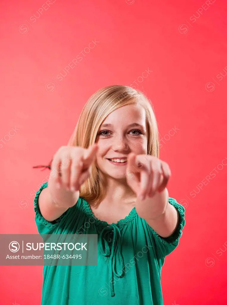 Smiling girl pointing both index fingers towards the viewer