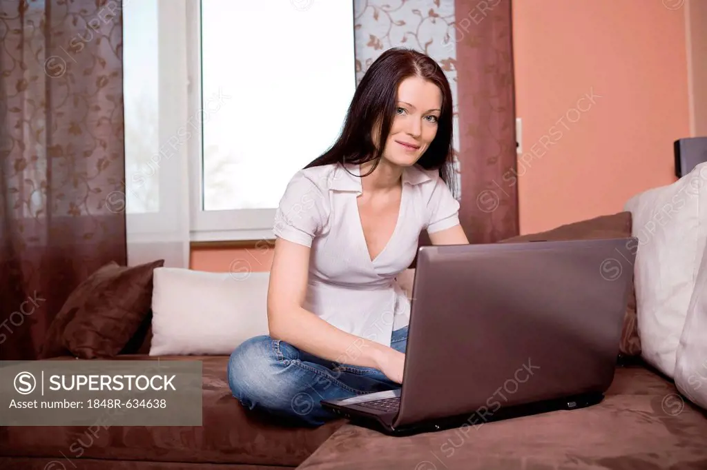 Young woman surfing the internet on a sofa