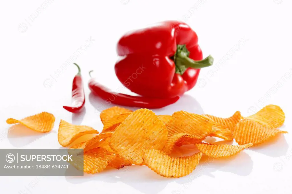 Paprika potato chips in front of a capsicum and chili peppers