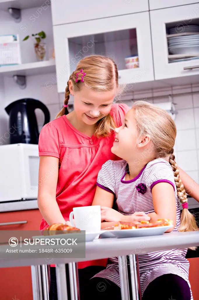 Two girls, sisters having breakfast in the kitchen