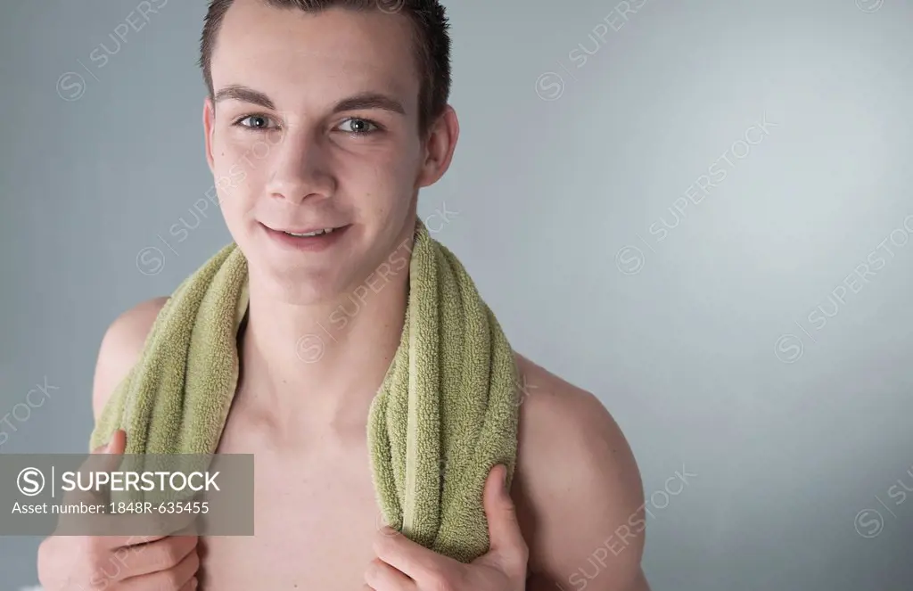 Young man with a naked torso and a towel wrapped around his shoulders