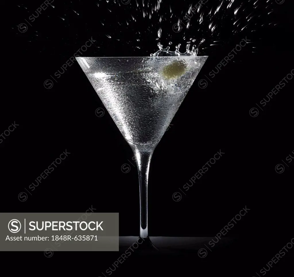 An olive creates a splash falling into a cocktail glass