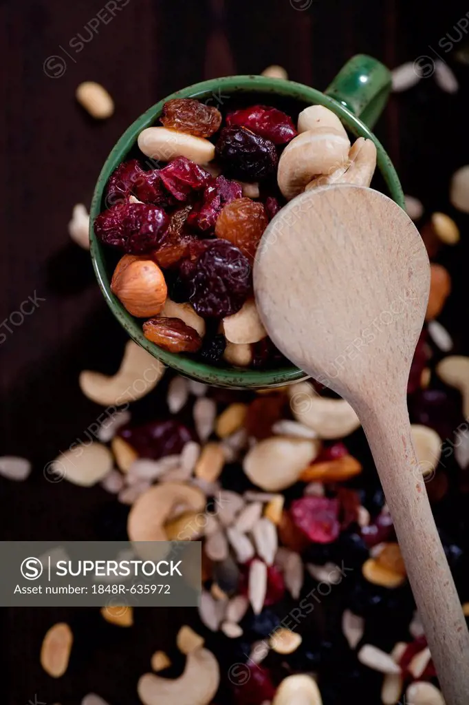 Various nuts, kernels, dried fruits, and a wooden spoon