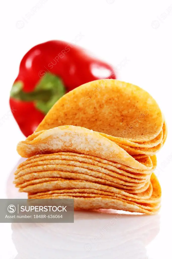 Oval paprika potato chips, stacking chips, stacked in front of a capsicum