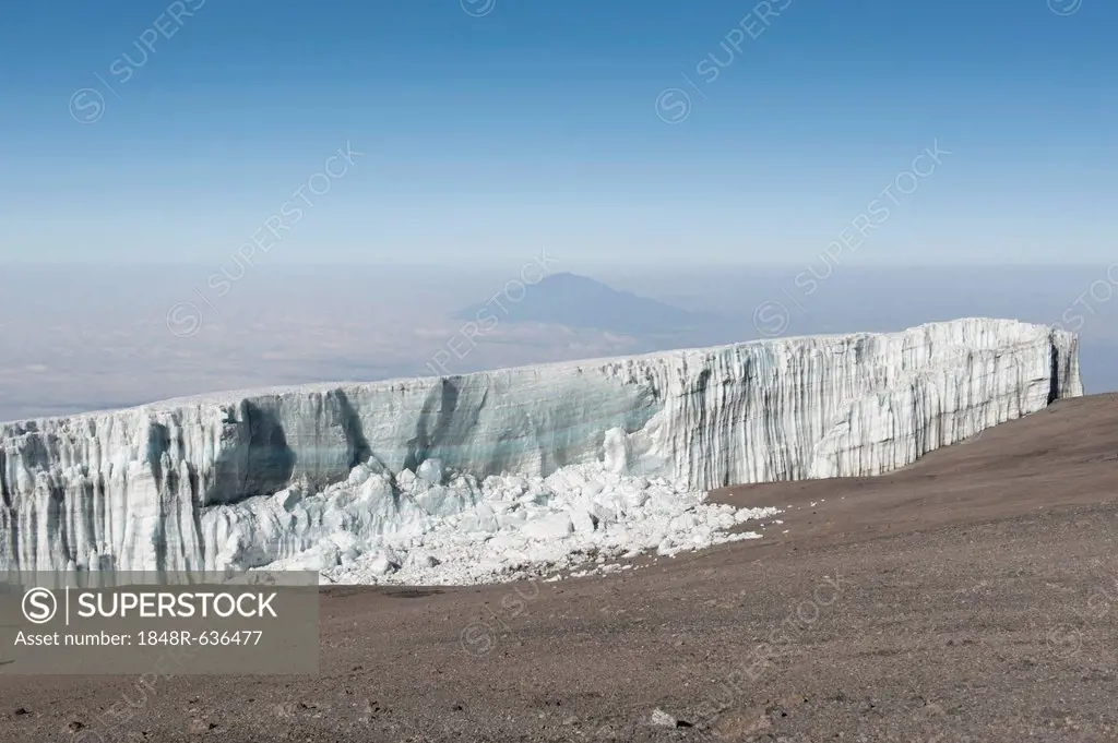 Melting ice, broken ice wall, Kersten glacier on the crater rim of Kibo, summit of Uhuru Peak, extinct volcano, with Mount Meru in the distance, Kilim...
