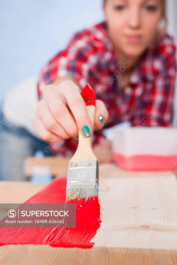 Young woman painting a board with a brush