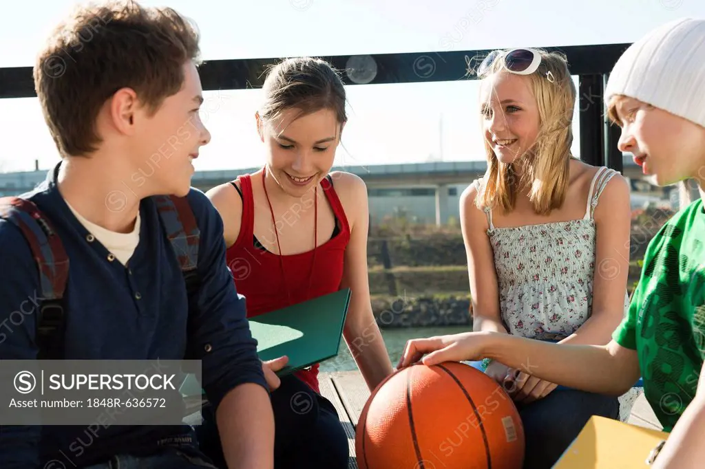 Four teenagers sitting on a boardwalk