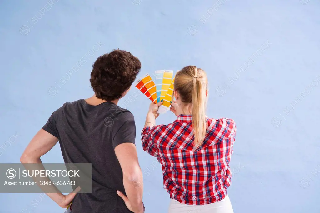 Young couple using colour cards to select a wall paint colour