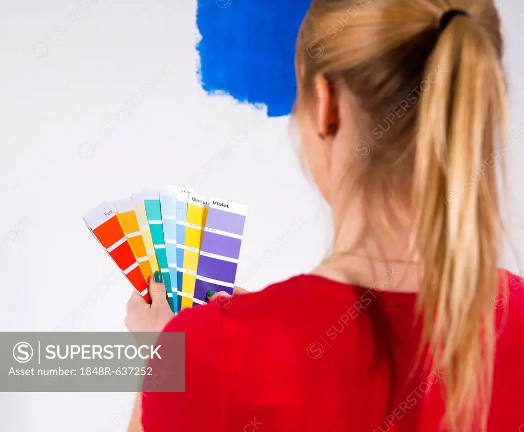 Young woman holding colour cards in front of a wall