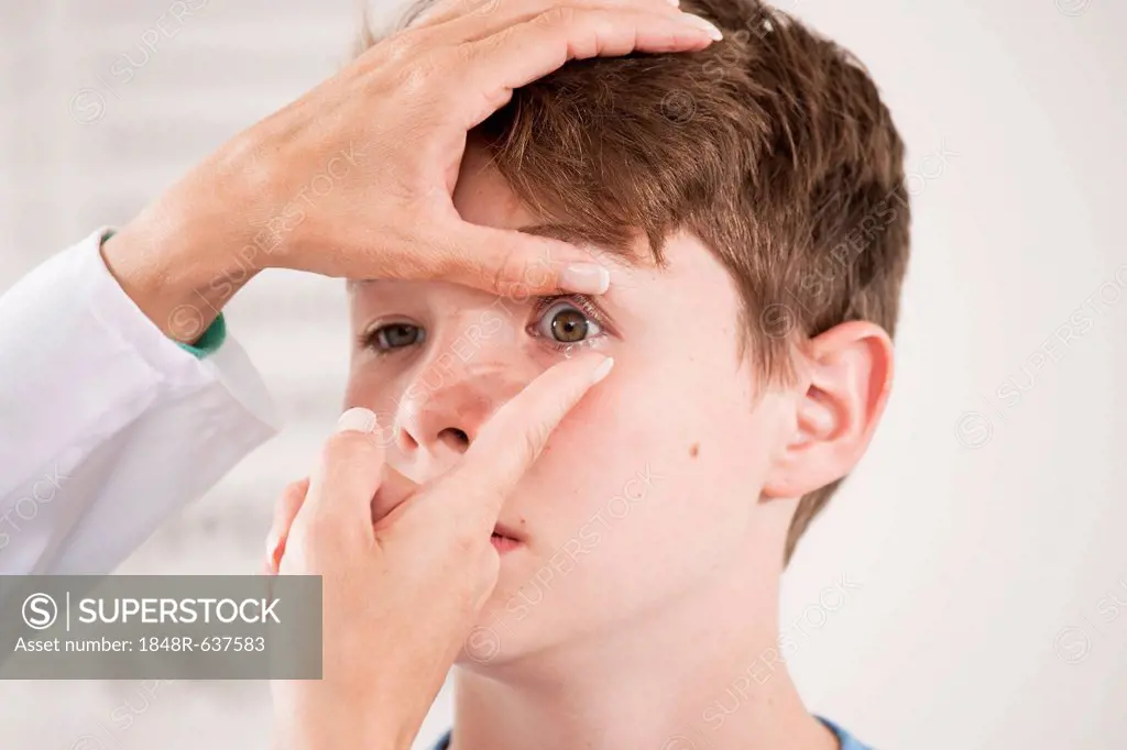 Ophthalmologist explaining the use of contact lenses to a teenage boy