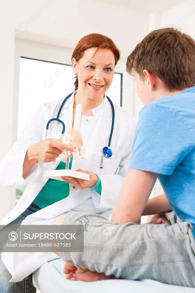 Orthopedic surgeon explaining a model of a foot to a teenage boy