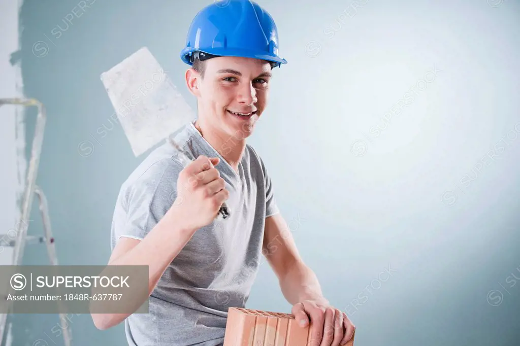 Young tradesman holding a trowel and a brick